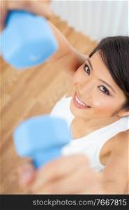 Beautiful Chinese Asian young woman or girl exercising with weightsblue dumb bells at home or in a gym