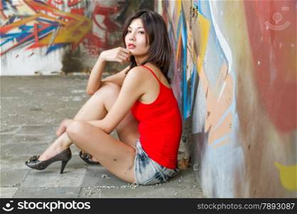 Beautiful Chinese woman sitting by graffiti walls