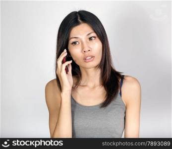 Beautiful Chinese woman talking on smartphone, looking serious