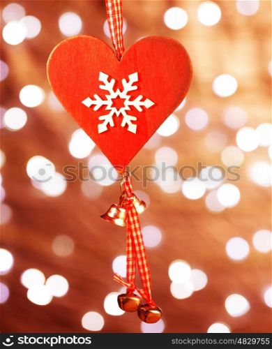 Beautiful Christmas decoration, red heart shaped toy with white snowflake ornament hanging on glowing background, wintertime holidays concept