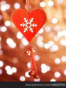 Beautiful Christmas decoration, red heart shaped toy with white snowflake ornament hanging on glowing background, wintertime holidays concept