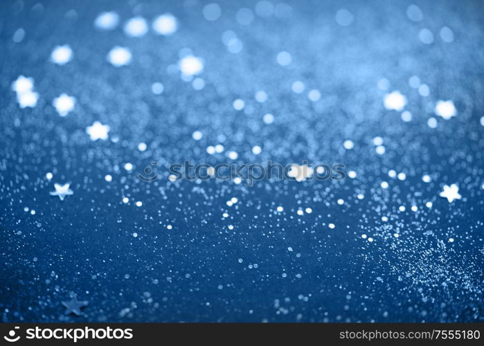 Beautiful Christmas light and stars background. Abstract glitter bokeh and scattered sparkles in classic blue, on black. Beautiful Christmas light background