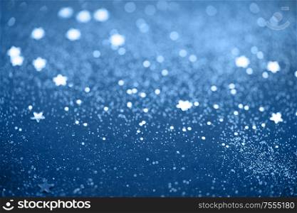Beautiful Christmas light and stars background. Abstract glitter bokeh and scattered sparkles in classic blue, on black. Beautiful Christmas light background