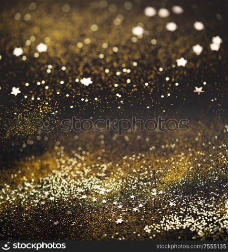 Beautiful Christmas light background. Abstract glitter bokeh and scattered sparkles in gold, on black square background. Beautiful Christmas light background.