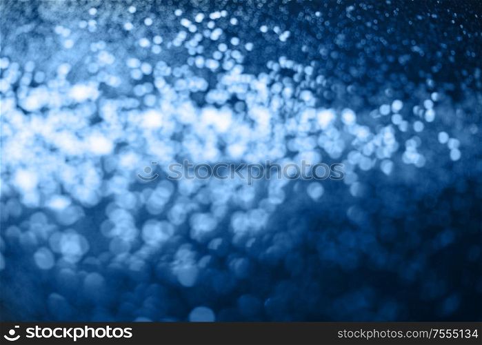 Beautiful Christmas multicolored defocused light background. Abstract classic blue glitter bokeh and scattered sparkles. Classic blue bokeh lights
