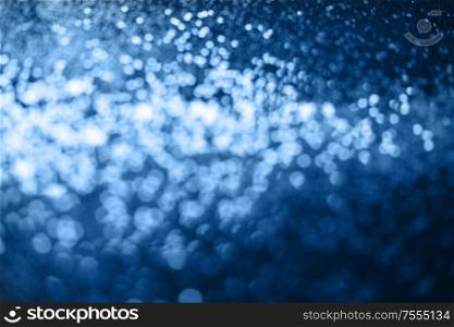 Beautiful Christmas multicolored defocused light background. Abstract classic blue glitter bokeh and scattered sparkles. Classic blue bokeh lights