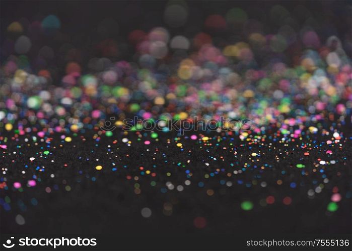 Beautiful Christmas multicolored light background. Abstract multicolored glitter bokeh and scattered sparkles , on black. Beautiful Christmas light background. Abstract glitter bokeh and scattered sparkles in gold, on black