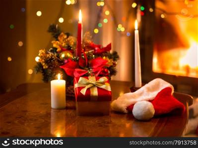 Beautiful christmas photo of burning candles with giftbox against fireplace