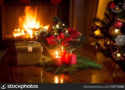 Beautiful Christmas wreath with red candles in living room with burning fireplace