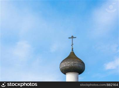Beautiful Church dome with a cross against a blue cloudy sky.