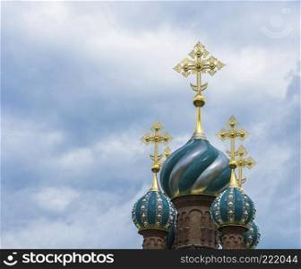 Beautiful church domes with gold crosses against a cloudy sky on a cloudy day. 