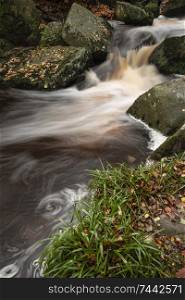 Beautiful close up of stream flowing over rocks in Autumn Fall forest landscape in Peak District in England