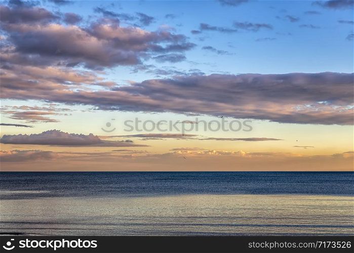 Beautiful colorful clouds over the sea. Stunning sky after sunset.
