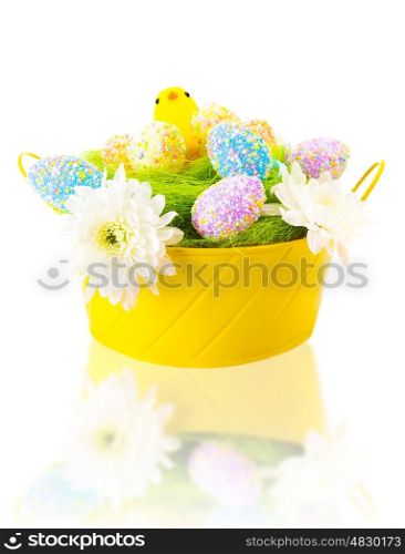 Beautiful colorful eggs with sweet chick in festive yellow basket isolated on white background, traditional Easter symbol