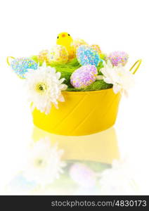 Beautiful colorful eggs with sweet chick in festive yellow basket isolated on white background, traditional Easter symbol