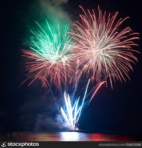 Beautiful colorful red and orange holiday fireworks on the black sky background