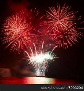 Beautiful colorful red and orange holiday fireworks on the black sky background