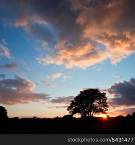 Beautiful colorful sunset in Summer over fields with lovely deep colors