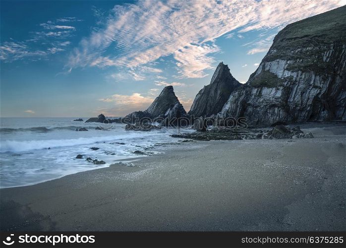 Beautiful colorful sunset over beach landscape with jagged rock formations