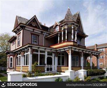 Beautiful colorful wooden Victorian style residential building with porch and balcony on a bright summer spring day.