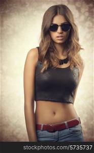 Beautiful, confident, young woman with sunglasses. She wear black top, jeans. She has got brown, curly hair.