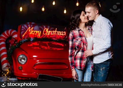 Beautiful couple in love hugging against the background of glowing lights and retro car. Studio portrait photo. Valentine’s day. Loving couple. Valentines day. Christmas holiday.. Beautiful couple in love hugging against the background of glowing lights and retro car. Studio portrait photo. Valentine’s day. Loving couple. Valentines day. Christmas holiday