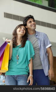 Beautiful couple in shopping mall looking away