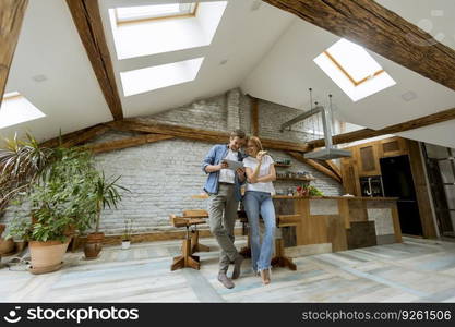 Beautiful couple is using a digital tablet and smiling while sitting on the table at home