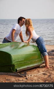 beautiful couple kissing on a beach near old boat