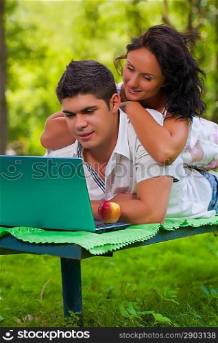 beautiful couple on bench with laptop
