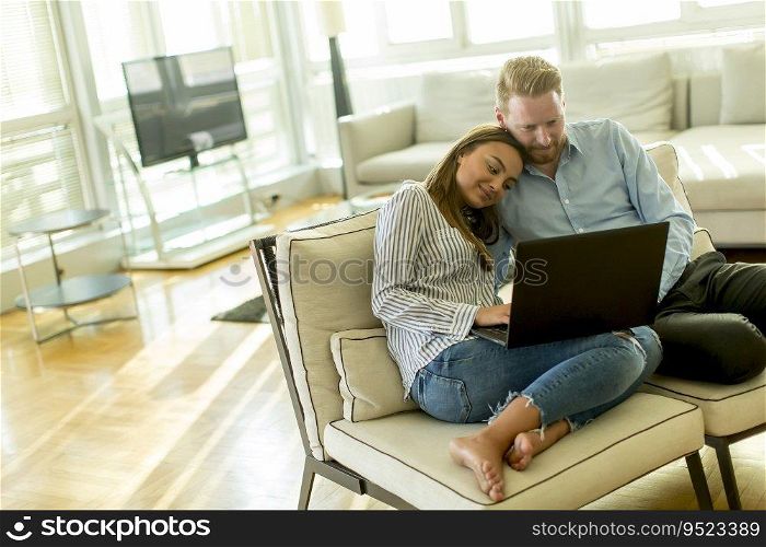 Beautiful couple sitting on the floor with laptop in the living room