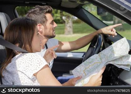 beautiful couple with map in car