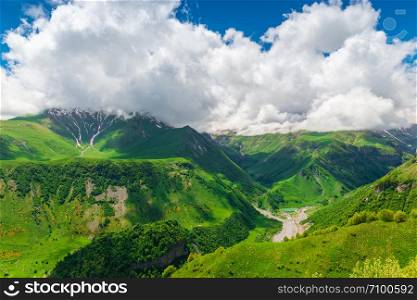 Beautiful cumulus clouds over the gorge and high mountains of the Caucasus in Georgia