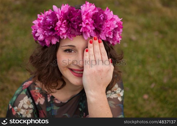 Beautiful curvy girl with a flower crown covering her eye in the landscape