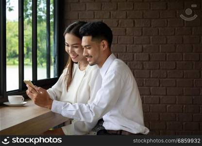 Beautiful cute love couple looking at smartphone together