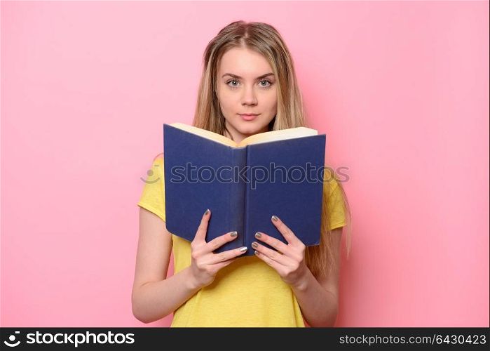 Beautiful cute woman reading book isolated on pink background