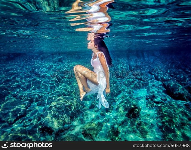Beautiful dance underwater, gorgeous sportive woman wearing long white dress, dive to clear blue sea, zen balance and meditation concept