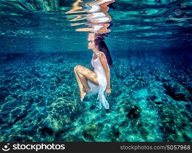 Beautiful dance underwater, gorgeous sportive woman wearing long white dress, dive to clear blue sea, zen balance and meditation concept