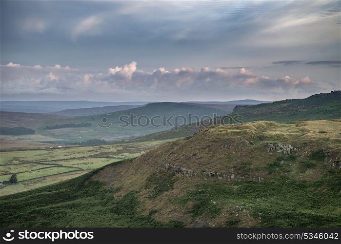Beautiful dawn sunrise landscape image from Higger Tor towards foggy Hope Valley in Summer in Peak District England