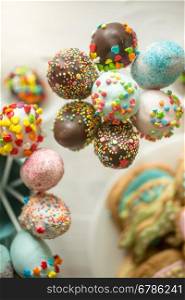 Beautiful decorated cake pops in cups on wooden table