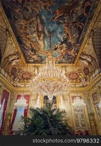 Beautiful decorated Napoleon apartments at Louvre palace. Royal family rooms with cardinal red curtains, golden ornate walls, paintings and crystal chandeliers suspended from ceiling