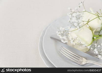 Beautiful decorated table with empty white plates, cutlery and white rose flowers on tablecloths, with space for text