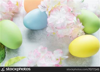 Beautiful delicate Easter composition with pink cherry flowers and multicolored Easter eggs on the stone background