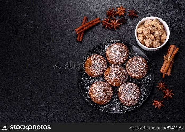 Beautiful delicious cupcakes with cocoa and raisins on a black concrete background. Time to drink tea. Beautiful delicious cupcakes with cocoa and raisins on a black concrete background