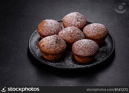 Beautiful delicious cupcakes with cocoa and raisins on a black concrete background. Time to drink tea. Beautiful delicious cupcakes with cocoa and raisins on a black concrete background