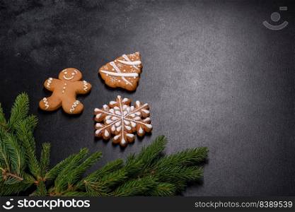 Beautiful delicious gingerbread gingerbread with Christmas tree branches on a dark concrete background. Preparing decorations for the Christmas table. Beautiful delicious gingerbread gingerbread with Christmas tree branches
