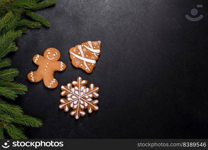 Beautiful delicious gingerbread gingerbread with Christmas tree branches on a dark concrete background. Preparing decorations for the Christmas table. Beautiful delicious gingerbread gingerbread with Christmas tree branches