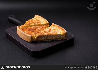Beautiful delicious quiche pie with four types of cheese with spices and herbs on a dark concrete background