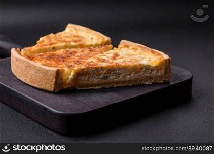 Beautiful delicious quiche pie with four types of cheese with spices and herbs on a dark concrete background