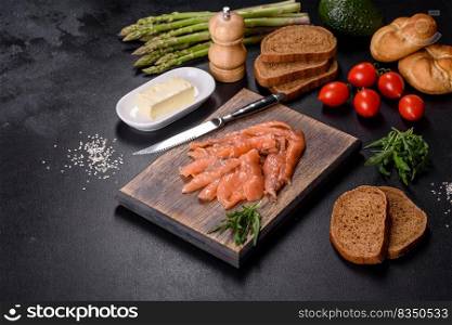 Beautiful delicious red fish slices on a wooden cutting board against a dark concrete background. Beautiful delicious red fish slices on a wooden cutting board
